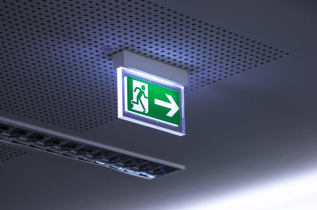 An image of a lit fire exit sign attached to an office ceiling